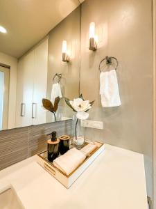 a bathroom with a vase of flowers and a mirror at Avant Spacious Sanctuary with the best view in BGC in Manila