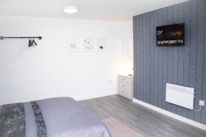 a bedroom with a bed and a tv on the wall at Central Eden Retreat (private room) in Liverpool