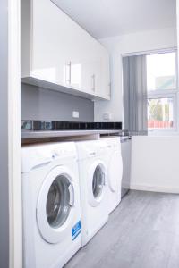 a white laundry room with a washer and dryer at Central Eden Retreat (private room) in Liverpool