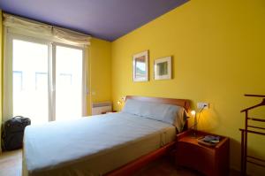 um quarto com uma cama e uma parede amarela em PORT 23 ATIC em L'Estartit