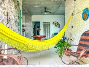 a yellow hammock on a porch with chairs and a table at Otima casa proxima a praia do Acuipe em Ilheus BA in Ilhéus