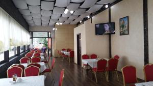 a dining room with red chairs and tables and a tv at Hotel Mondial - Eforie Nord in Eforie Nord