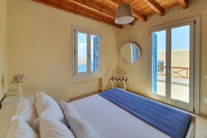 a bedroom with a bed and two windows at Monolithos Villas in Kipri