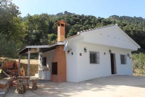 - un petit bâtiment blanc avec une cheminée au-dessus dans l'établissement CASA ENCINA, à Tolox