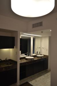 un bagno con tre lavandini e un grande specchio di Hotel BA Abasto a Buenos Aires