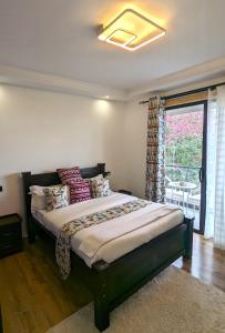 a bedroom with a bed with pillows and a window at Urban Haven 3BR Apartment in Nairobi