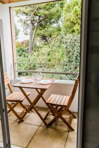 佩羅勒的住宿－Beau studio neuf + parking et vélo gratuit，阳台配有桌椅和窗户