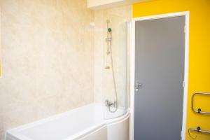 La salle de bains est pourvue d'une baignoire blanche et d'une douche. dans l'établissement Chill Nexus Oasis, à Liverpool