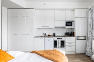 a white kitchen with white cabinets and a bed at Koda Apartment - Balcony - Great design and location in Rovaniemi
