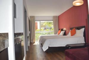 um quarto de hotel com duas camas e uma parede vermelha em Hotel BA Abasto em Buenos Aires