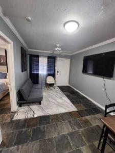 Blue Shark G9 - Midtown 1BR King Suite في هيوستن: غرفة معيشة مع أريكة وتلفزيون بشاشة مسطحة