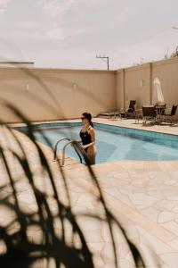 a woman standing next to a swimming pool at Firenze Hotel Votuporanga - Próximo ao Assary clube de Campo e o Centro de lazer do trabalhador - By Up Hotel in Votuporanga