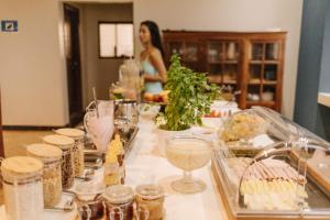 a woman is standing in a kitchen with a table with food at Firenze Hotel Votuporanga - Próximo ao Assary clube de Campo e o Centro de lazer do trabalhador - By Up Hotel in Votuporanga