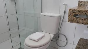 a white toilet in a bathroom with a shower at Pousada Bomar Bombinhas in Bombinhas