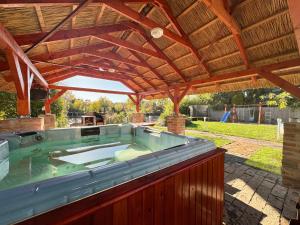 una gran bañera de hidromasaje bajo un techo de madera en Relax & Fishing, en Békésszentandrás