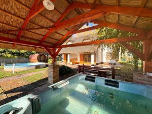 an outdoor swimming pool under a wooden roof at Relax & Fishing in Békésszentandrás