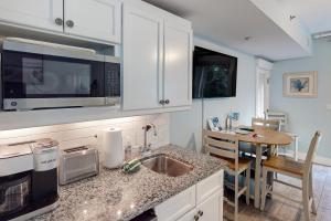a kitchen with a sink and a microwave and a table at Lasata 3204 in Destin