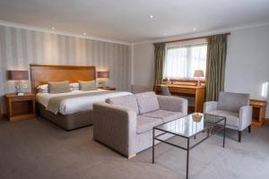 a hotel room with a bed and a couch and chair at Dale Hill Hotel in Ticehurst