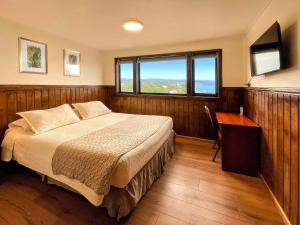 Un dormitorio con una cama y un escritorio y una ventana. en Hotel Bután Coronel, en Coronel