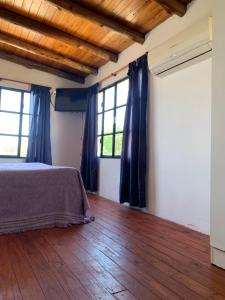 1 dormitorio con 1 cama, suelo de madera y ventanas en Costa del Uruguay II, en Colón