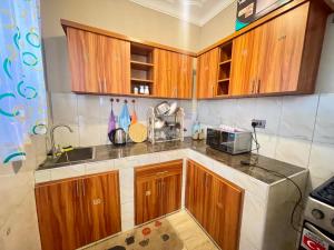 a kitchen with wooden cabinets and a sink at Treat Homies 2 in Kira