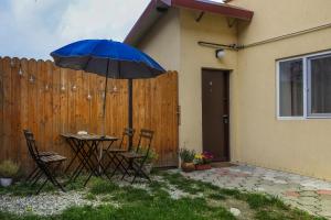 a table and chairs with an umbrella in front of a fence at Mill Central Apartment in Sibiu