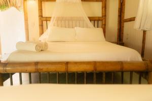 Una cama con sábanas blancas y toallas. en Playa Bonita Hotel EcoCabañas Tayrona en Buritaca