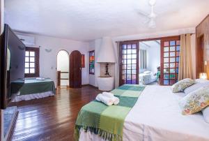 1 dormitorio con 1 cama grande y TV en Pousada Recanto da Villa, en Ilhabela