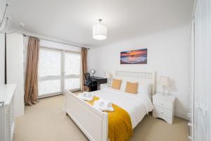 a white bedroom with a bed and a desk at Deluxe 2Bed Duplex Apartment & parking in London