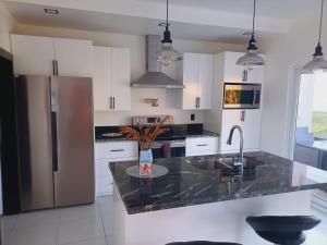 uma cozinha com armários brancos e um balcão de granito em Coral Views Village - uMaMi em French Harbor