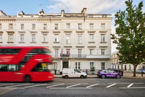 un autobus rosso a due piani di fronte a un edificio di Huttons Hotel, Victoria London a Londra