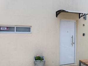a white building with a door and a potted plant at Casita de Piedra 11 in Trinidad