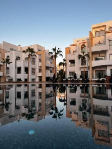 una piscina de agua con palmeras y edificios en Dominium Residence en Agadir