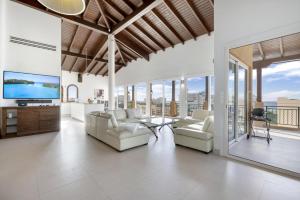 a living room with couches and a tv and windows at Fine 3 BR Oceanview Penthouse in Prime Location - La Perla Sky in Cupecoy