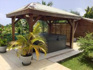 a wooden gazebo with a couch in a garden at VILLA ALIZÉE APPARTEMENT 3 in Sainte-Rose