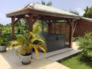 a wooden gazebo with a couch in a garden at VILLA ALIZÉE Logement 3 in Sainte-Rose
