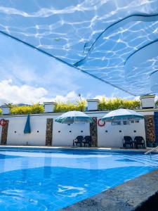 einen Pool mit Stühlen und Sonnenschirmen neben einem Gebäude in der Unterkunft Hosteria La Medusa in Cocorná