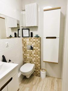 a white bathroom with a toilet and a sink at Apartament Ełk Centrum II in Ełk