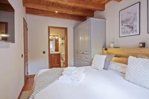 Un dormitorio con una cama blanca con toallas. en Luderna - Apartamento con jardín Pleta de Arties Montardo, en Arties