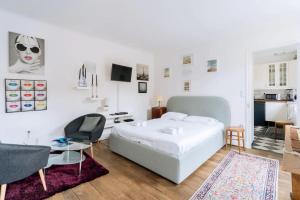 パリにあるCosy 1 Bedroom in the heart of Montparnasseの白いベッドルーム(ベッド1台、テーブル、椅子付)