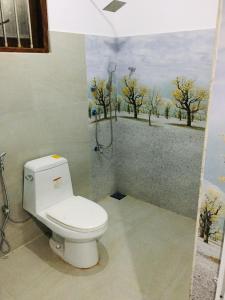 a bathroom with a toilet and a painting on the wall at Tropical Villa in Galle