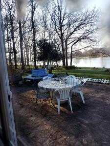 une table de pique-nique et des chaises avec un lac en arrière-plan dans l'établissement Le Sanctuaire, à Missillac