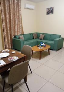sala de estar con sofá verde y mesa en La Couronne Suites, en Bangui