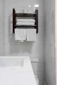 Baño blanco con toallas blancas en un estante en Hotel Cuenca, en Cuenca