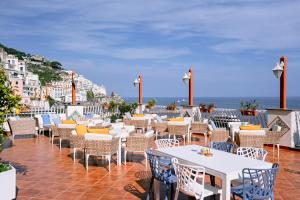 un restaurante con mesas y sillas y el océano en Hotel La Bussola, en Amalfi