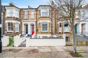 a large brick house with a red door at Ickburgh Road Guesthouse in London