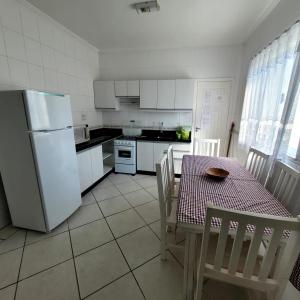cocina con mesa y nevera blanca en Bombinhas Brasil Residence Tourist Home no Centro de Bombinhas, en Bombinhas