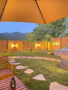 a patio with an umbrella and a bench on the grass at Sapanca360bungalows in Sakarya