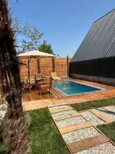 un patio trasero con piscina, mesa y sombrilla en Sapanca360bungalows, en Sakarya
