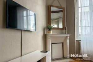 ein Wohnzimmer mit einem TV und einem Kamin in der Unterkunft The House of Monthléry Comfort in Limoges in Limoges